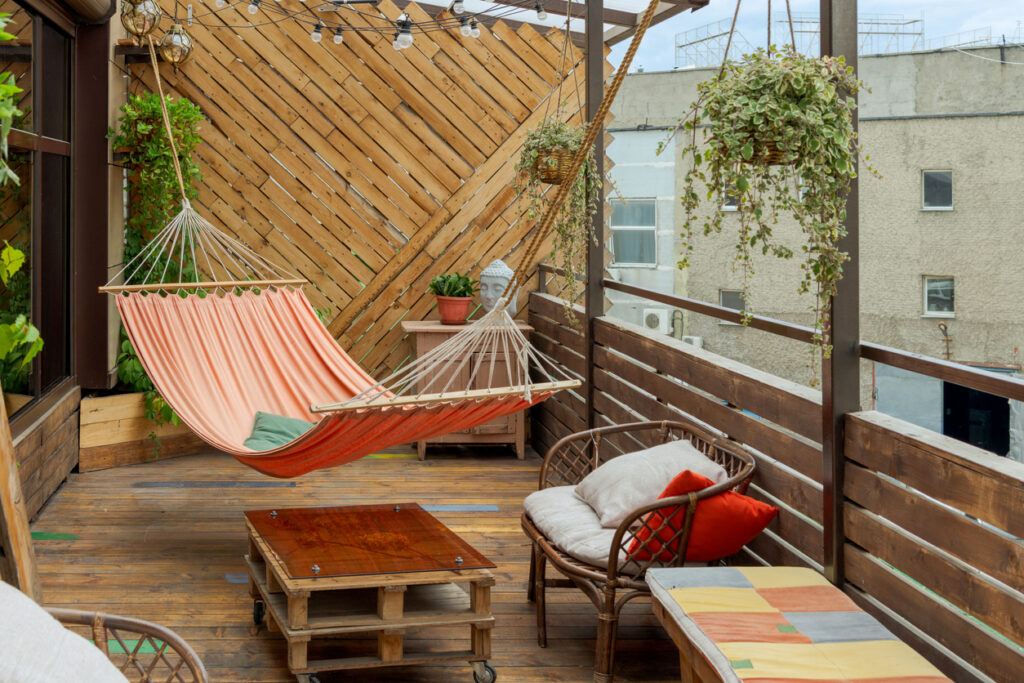 A hammock hanging on a wooden deck, in a city.