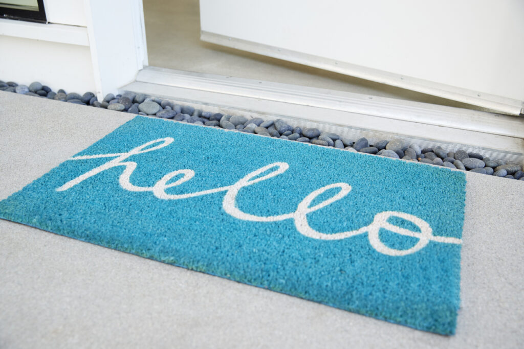 A blue doormat with the word "hello" written on it, inviting guests to enter.